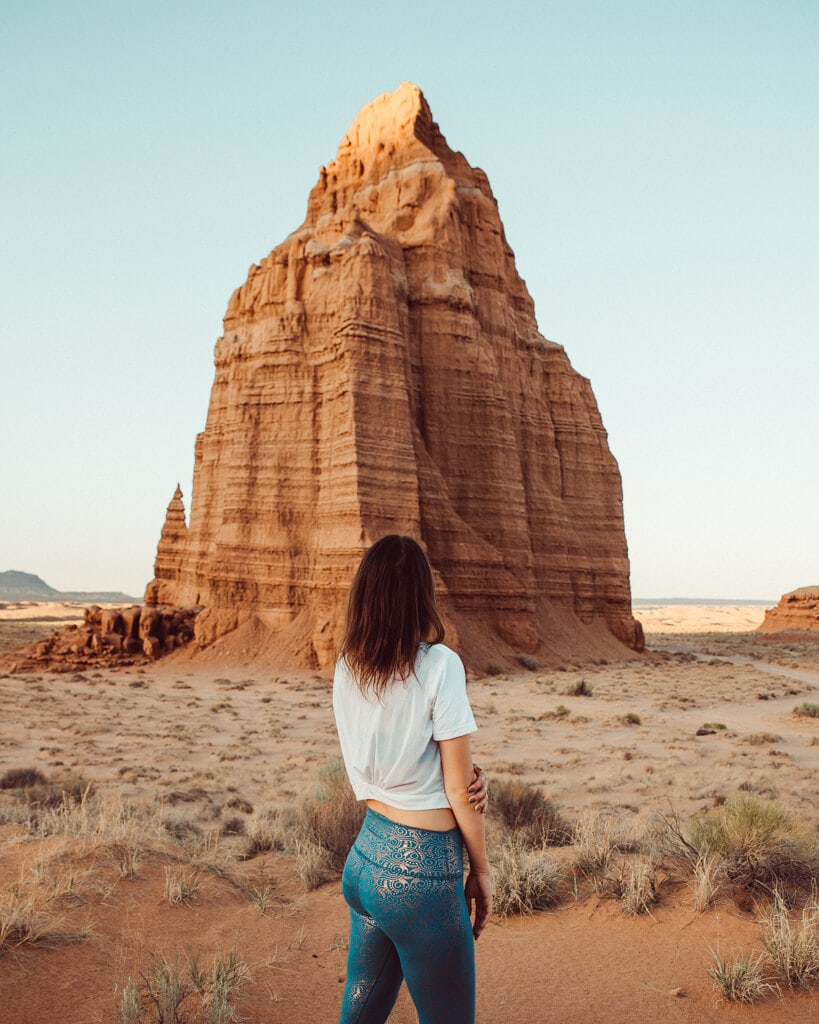 girl standing in front of a rock formation on cathedral valley road in capitol reef