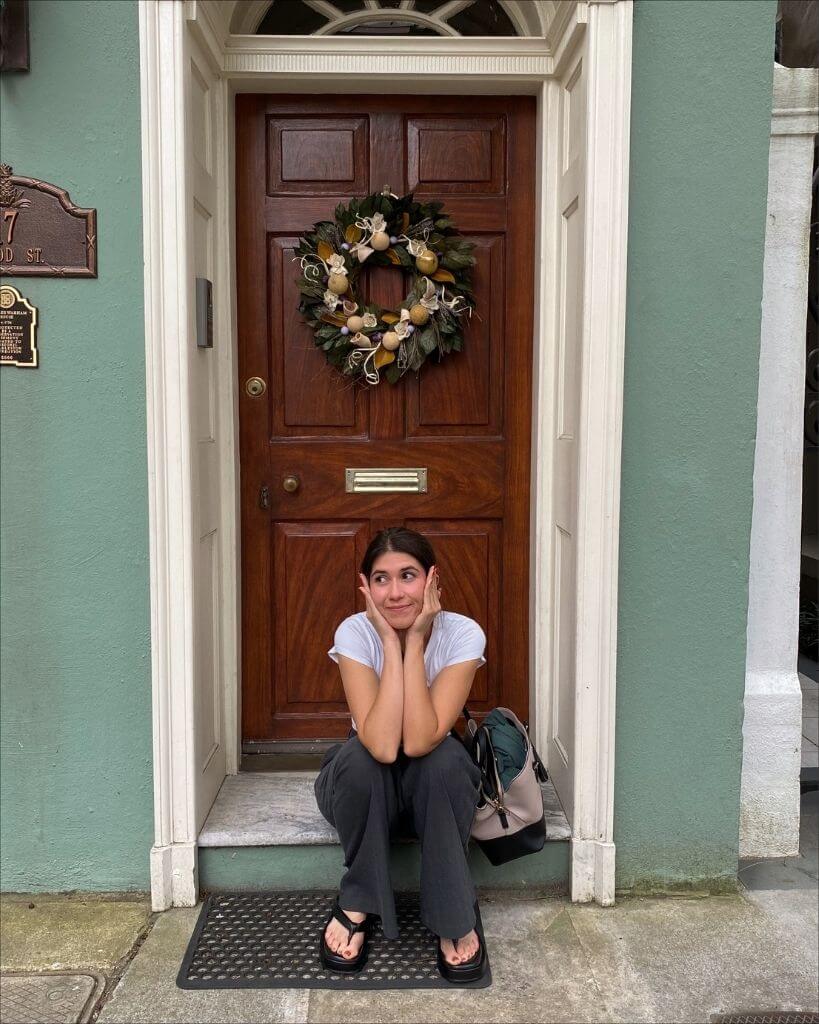 girl sitting in front of a blue house in charleston south carolina