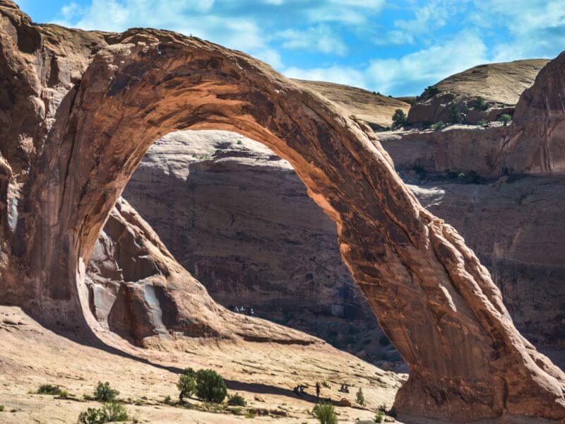 a sunny day over corona arch in moab utah