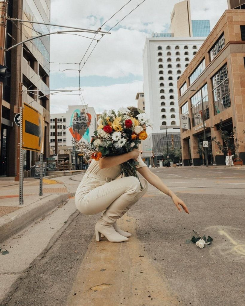 girl holding flowers standing in a road in downtown phoenix