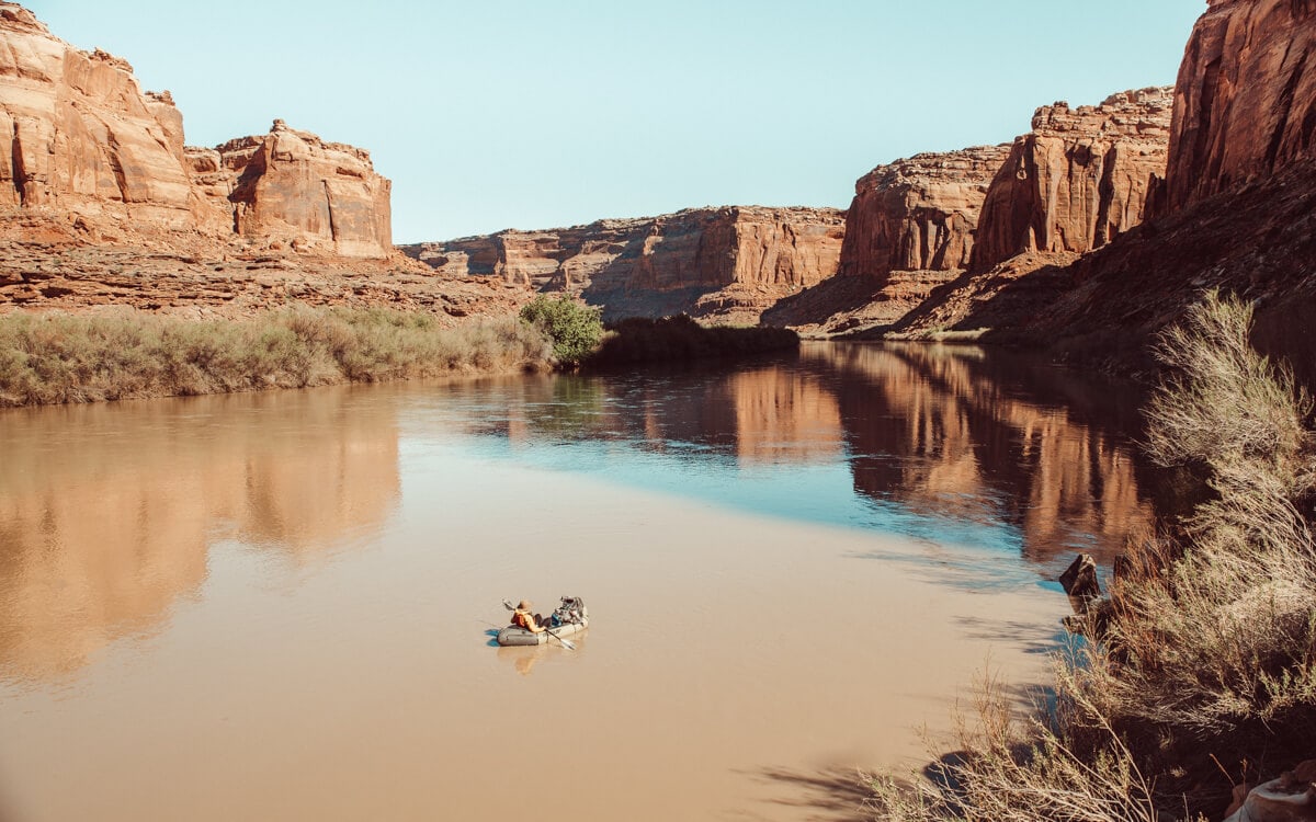 girl riding a packraft through moab utah's green river