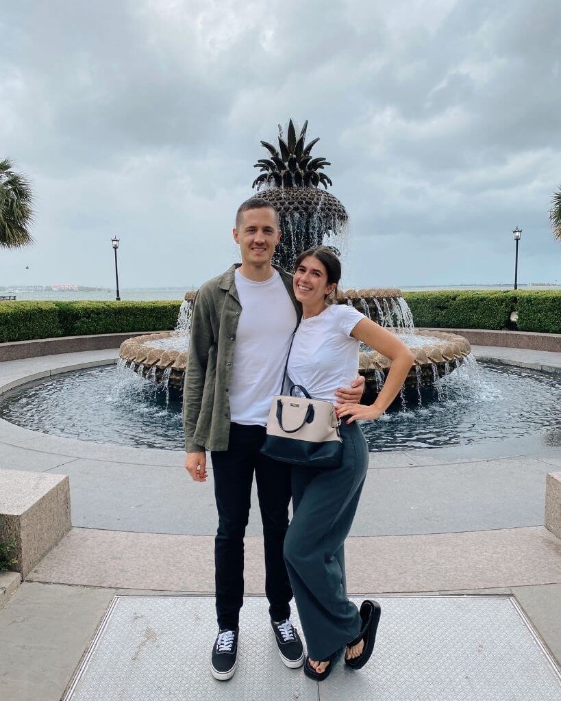 couple standing in front of the pineapple fountain in charleston