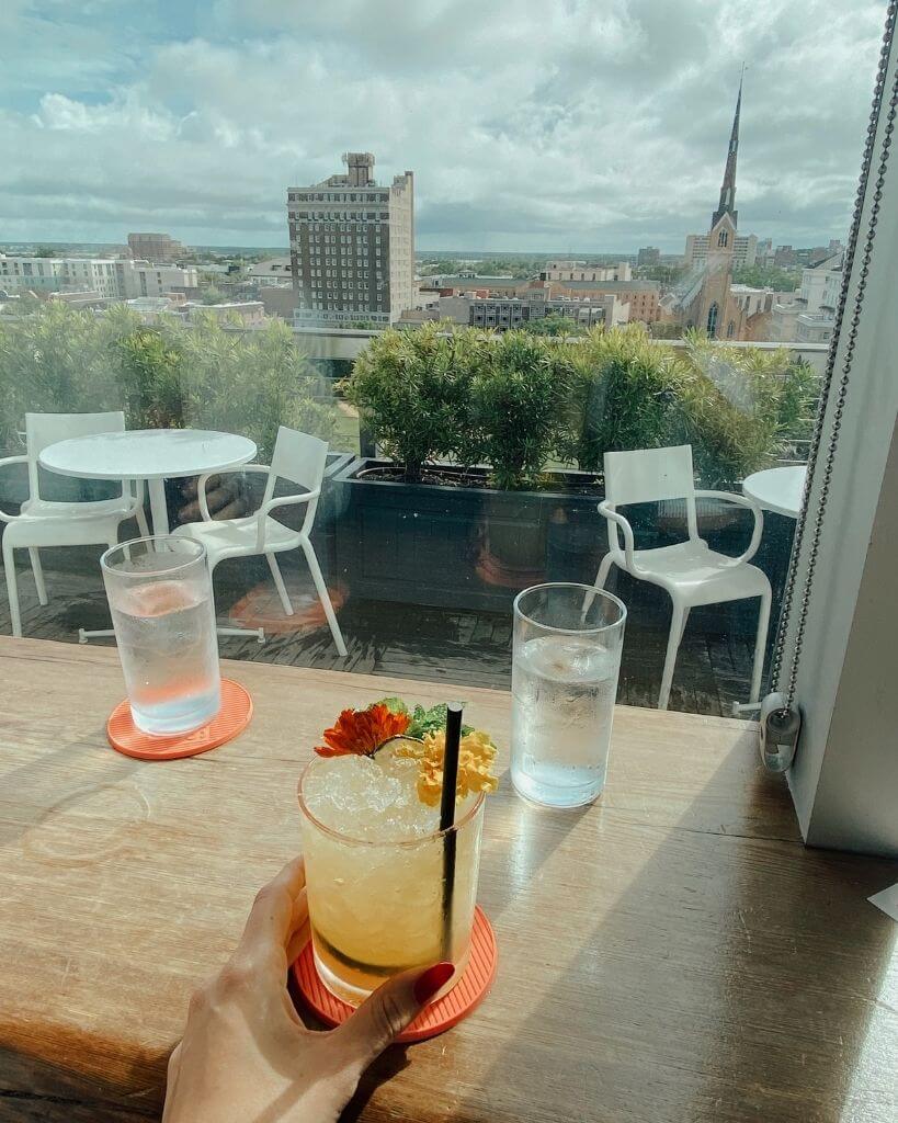 girl drinking a mai tai and looking over the rooftop of the citrus club in charleston south carolina